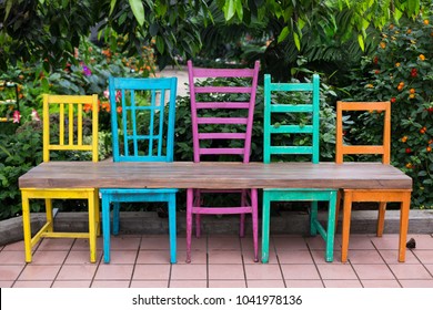 Bench made of five wood chairs in different sizes and colours and wood plank