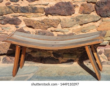 A Bench Made From Old Wine Barrel Staves Shown Against A Stone Wall