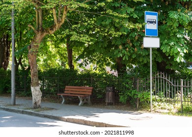 A bench near the bus stop with trees. An old bus parking lot with a bench.