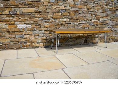 Bench On A Stone Terrace In Front Of Stone Wall