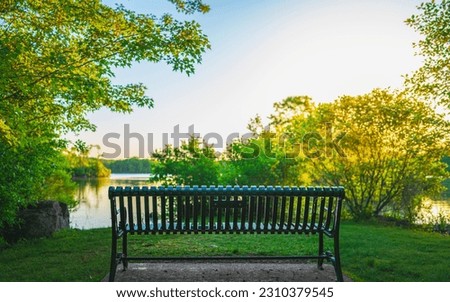 Bench in the park at sunset. Tranquil woodland landscape over Olney Pond at Lincoln Woods State Park Beach in Providence, Rhode Island