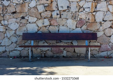 Bench Seat Against City Wall In A Park With Trees Overhead