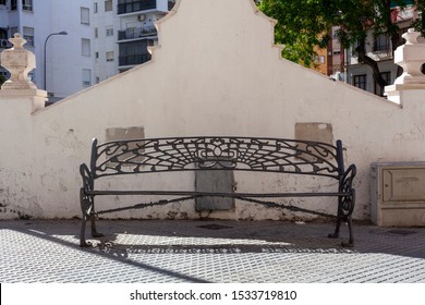 Bench Seat Against City Wall In A Park With Trees Overhead