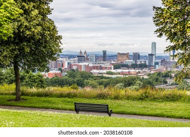 A Bench Seen Lbetween Trees Overlooking The Liverpool Skyline From Everton Park.