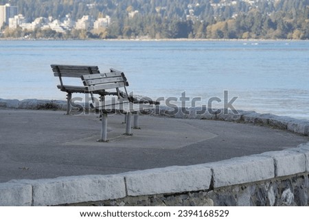 Benches looking at the Burrard Inlet near the Girl in a Wetsuit sculpture and Lions Gate Bridge at Stanley Park during a fall season in Vancouver, British Columbia, Canada