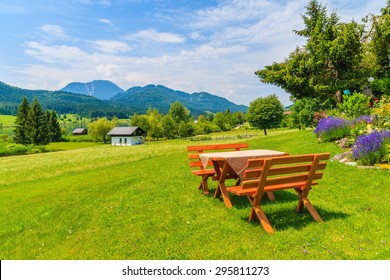 Benches with picnic table on green grass in alpine village on shore of Weissensee lake in summer landscape of Alps Mountains, Austria