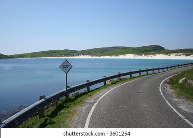bend in coastal road with white sand