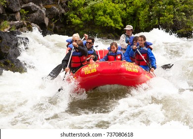 Bend, Oregon - 6/12/2009: group of people white water rafting in a rubber raft on the Deschutes River at  Big Eddy rapid - a class 4 rapid.