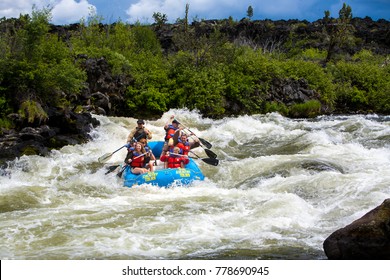 Bend, Oregon - 6/12/2009: group of people white water rafting in a rubber raft on the Deschutes River at  Big Eddy rapid - a class 4 rapid - near Bend.