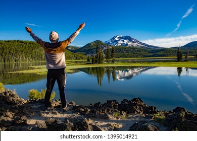 Bend, Oregon - 7/6/2016:  A young man offering praise to the south sister mountain, looking accross Sparks lake in the Oregon cascade mountains on century drive near Bend, Oregon
