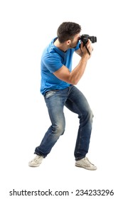 Bend young man taking photo with digital camera side view. Full body length portrait isolated over white background.