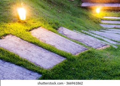 Bending garden stone path at night with glowing light from garden outdoor light
