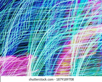 Bending light trails with wind effect, like tall plants in a breeze, in an ornamental garden with festive holiday illumination at night. Long exposure with motion blur. Painting with light.