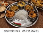 Bengali style thali spread verity cuisine hilsa fish vegetable beef mutton egg curry fry vorta mashed chicken liver sweet yogurt side dish served on rustic metal tin stainless steel plate small bowls