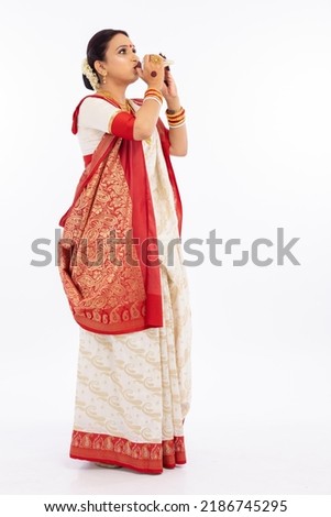 Bengali woman blowing on a conch shell 