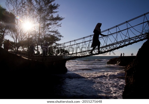 Bengkulu, Indonesia - 12-10-2014: People\
crossing wooden bridge at Sungai Suci Beach, one of popular tourist\
destination in Bengkulu,\
Indonesia
