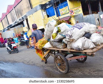 Bengkulu, Indonesia - September 27, 2019: Old Man Pulling Wooden Wagon Full Of Plastic Sack.