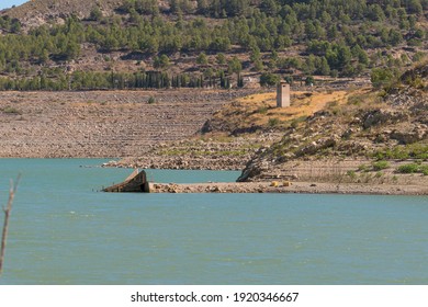 Beninar reservoir between mountains in southern Spain, there is an old building, there is vegetation of shrubs and trees