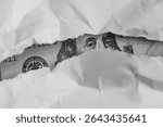 Benjamin Franklin macro peeking through torn white paper