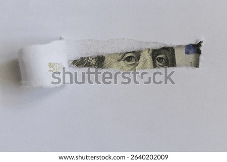 Benjamin Franklin macro peeking through torn white paper