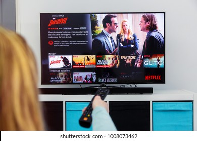 Benon, France - January 21, 2018: Woman Holding A TV Remote Control And Play Dardevil, A Marvel Film That Is An Original Creation Of Netflix Industry. 