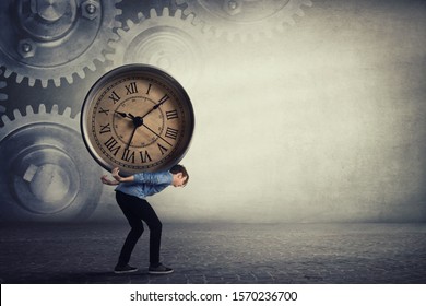Bent down guy carrying a big heavy clock on his back. Overloaded student tired of daily tasks, and difficult burden. Time pressure and management concept, schedule efficiency, planning and control.