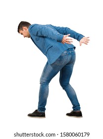 Bent down young man keeps hands back as carrying an heavy invisible object on his shoulders isolated on white background. Overloaded boy tired of daily routine, difficult task and burden concept.