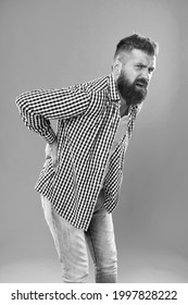 Bent over feeling sharp pain in back. Bearded man suffer from pain shoots. Back posture. Back bone. Back pain prevention. Health care. Medical problem. Complaint and disease. Trauma and injury