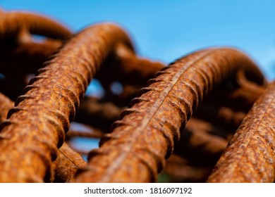 Bent And Rusty Iron Rods Or Steel Reinforcements On A Building Site With Sunlight And Blue Sky, Selective Focus And Vanishing Point. Macro Close Up Of Corroded Metal With Warm Orange Surface Color.