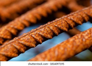 Bent And Rusty Iron Rods Or Steel Reinforcements On A Building Site With Sunlight And Blue Sky, Selective Focus And Vanishing Point. Macro Close Up Of Corroded Metal With Warm Orange Surface Color.