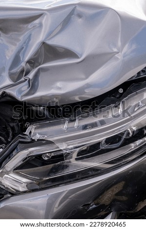 Bent sheet metal and damaged elements of a broken gray car