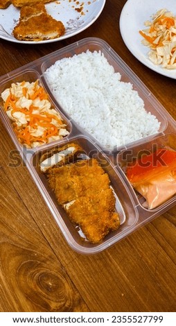 bento menu or lunch menu which contains fried chicken breast coated in breadcrumbs, carrot cabbage salad, mayonnaise sauce, tomato sauce, white rice