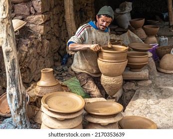 Berber village, Morocco - March 27, 2022: Berber potter uses foot-powered wheel to form tagines and clay ovens for sale in local village.