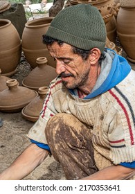 Berber village, Morocco - March 27, 2022: Berber potter uses foot-powered wheel to form tagines and clay ovens for sale in local village.