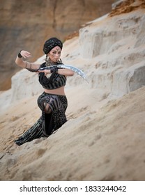 Berber woman in black clothes dancing with a saber on the sand