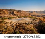 Berca mud volcanoes creating a unique geological formation amidst rolling hills and colorful autumn trees