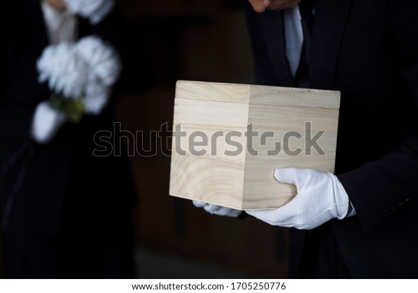 Bereaved holding urn at\
funeral
