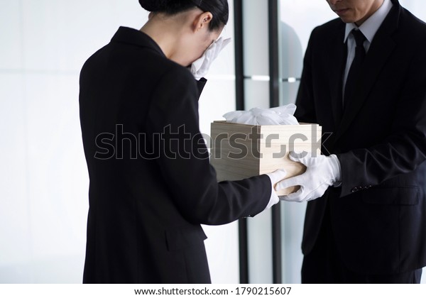 Bereaved holding urn at\
funeral
