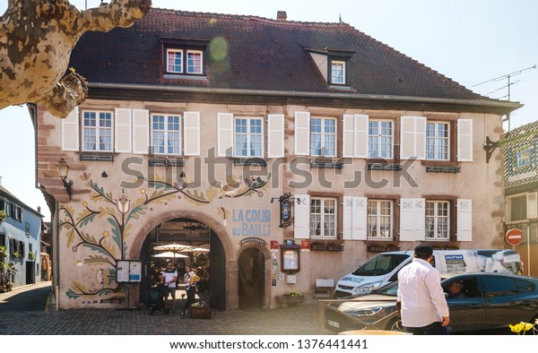Bergheim,
France - 19 Apr 2019: Young family with toddle exits restaurant
cafe Hotel Residence La Cour Du Bailli on Grand Rue on a warm
spring day sightseeing the French
village