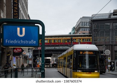 Berlin, Germany - 11th December 2019: Street View On Friedrichstraße Railway Station, Train, Yellow Tramway And People Passing By.