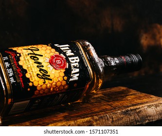 Berlin, GERMANY - 26 November, 2019: Jim Beam Honey Whiskey bottle on a rustic background with splashes of water.