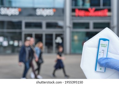 BERLIN, GERMANY- April 12, 2021: Antigen Flash Test And An FFP2 Mask Hold By A Hand With Glove In Front Of A Shooping Mile With New Yorker, Out Of Focus Shallow Depth Of Fields Berlin Germany