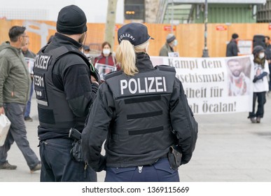 BERLIN, GERMANY APRIL 13, 2019: A German Female Police Officer Standing In Front Of A Group Of Protestors In Berlin During A Silent Demonstration For Abdullah Öcalan 