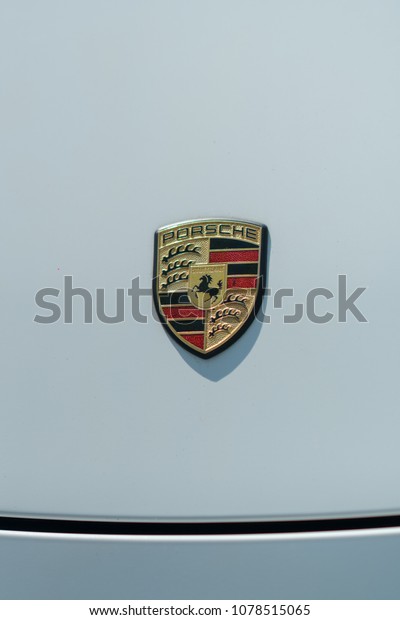 Berlin,\
Germany - April 18, 2018: Porsche emblem on a white car. Porsche AG\
is a German automobile manufacturer specializing in\
high-performance sports cars, SUVs and\
sedans