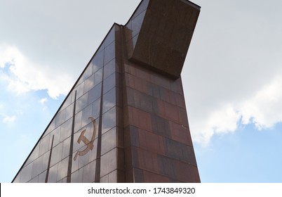 BERLIN, GERMANY - APRIL 29, 2016: The Soviet hammer and sickle symbol of the left red granite entrance building at the Soviet Memorial Park in Treptower Park on a sunny cloudy day.