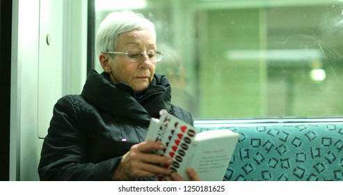 BERLIN, GERMANY, CIRCA JANUARY 2018 - Candid Authentic Real Life Of Older Woman Reading Inside Subway Train