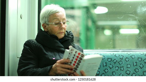 BERLIN, GERMANY, CIRCA JANUARY 2018 - Candid Authentic Real Life Of Older Woman Reading Inside Subway Train