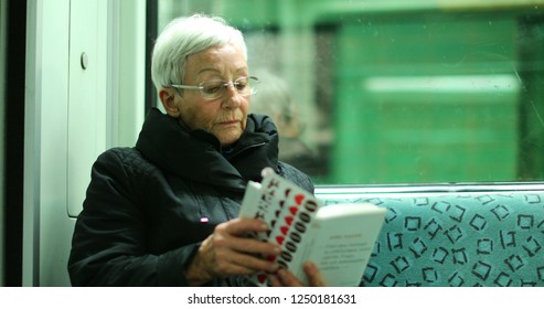 BERLIN, GERMANY, CIRCA JANUARY 2018 - Candid Authentic Real Life Of Older Woman Reading Inside Subway Train