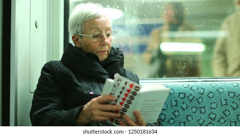 BERLIN, GERMANY, CIRCA JANUARY 2018 - Candid Authentic Real Life Of Older Woman Reading Inside Subway Train