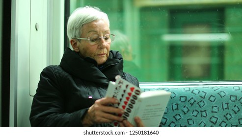 BERLIN, GERMANY, CIRCA JANUARY 2018 - Candid Authentic Real Life Of Older Woman Reading Inside Subway Train